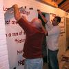 Tedrowe and Doug remove a stencil to reveal the finished quote.